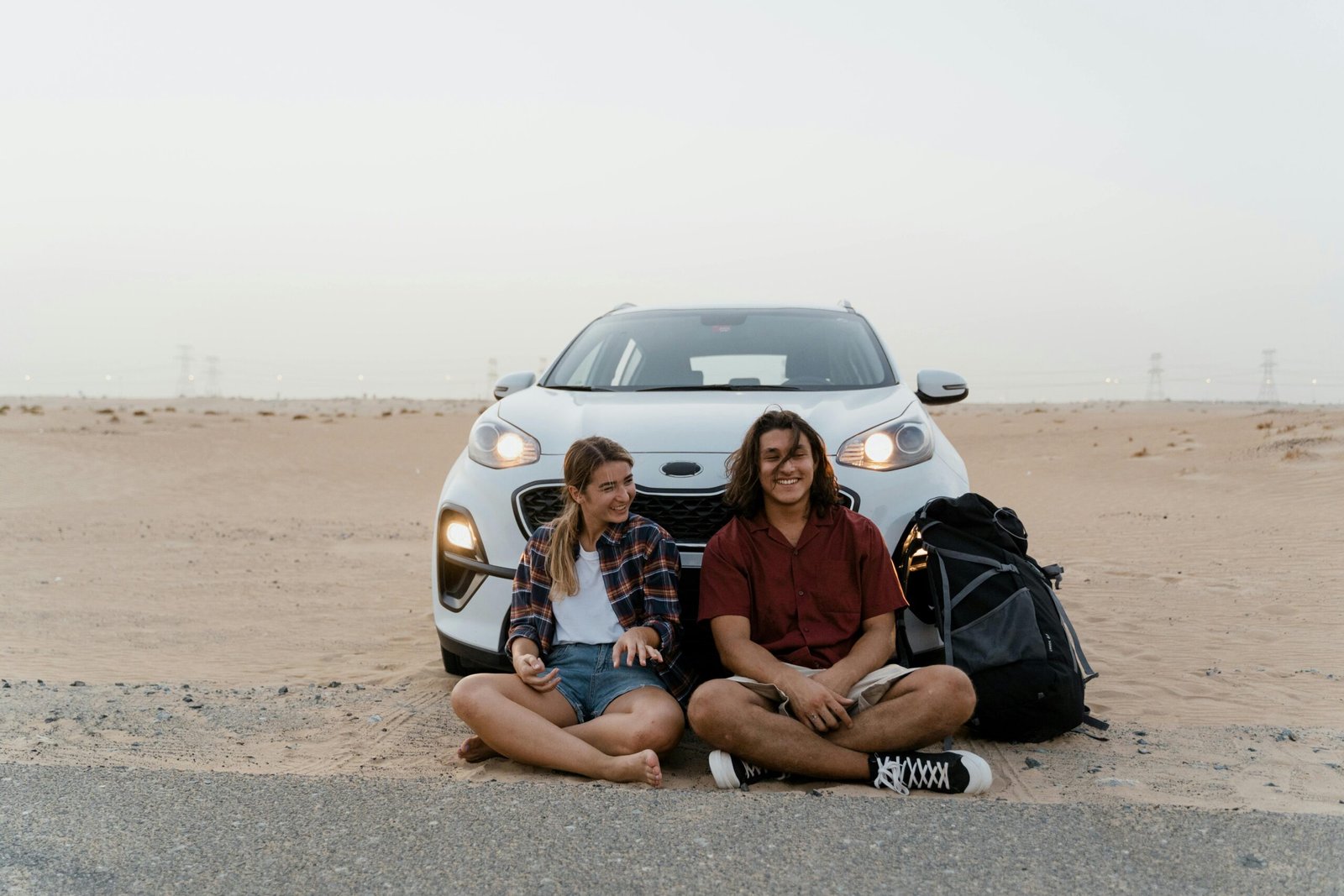 pexels-photo-8869383-8869383 Young travelers relaxing by their car in the desert, enjoying a scenic road trip adventure.